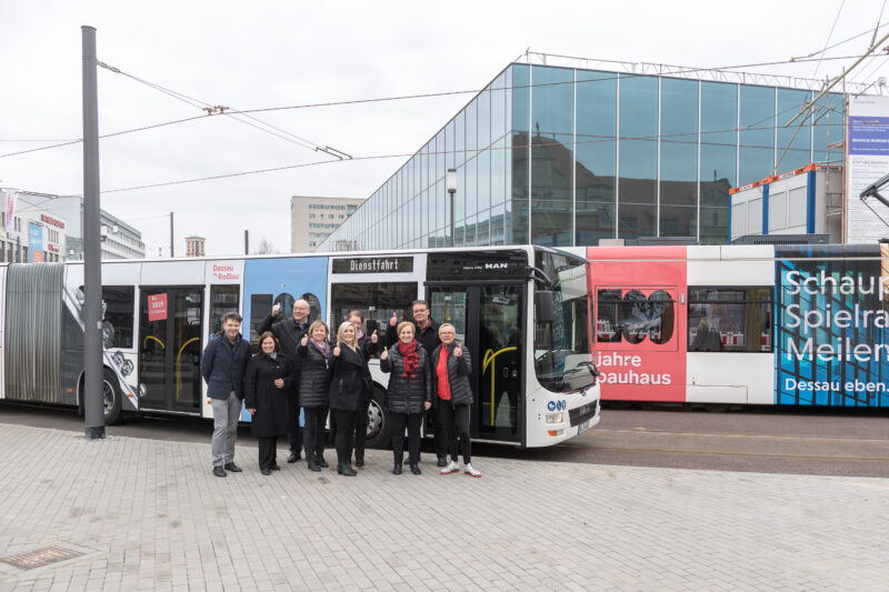 Projektbeteiligte vor den gebrandeten Straßenbahnen